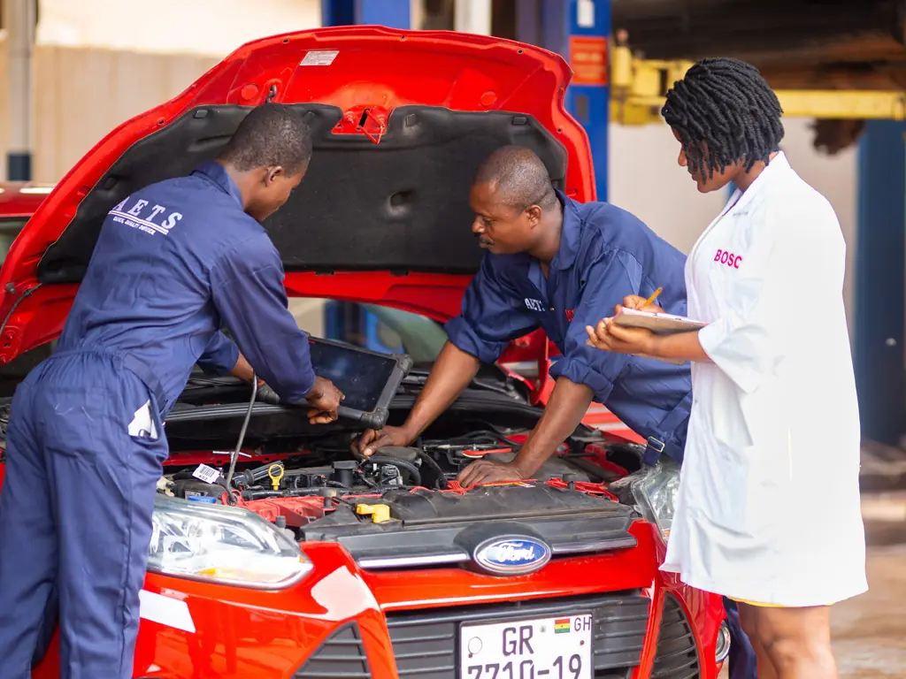 AETS technicians running a diagnostic on a red Ford in the workshop