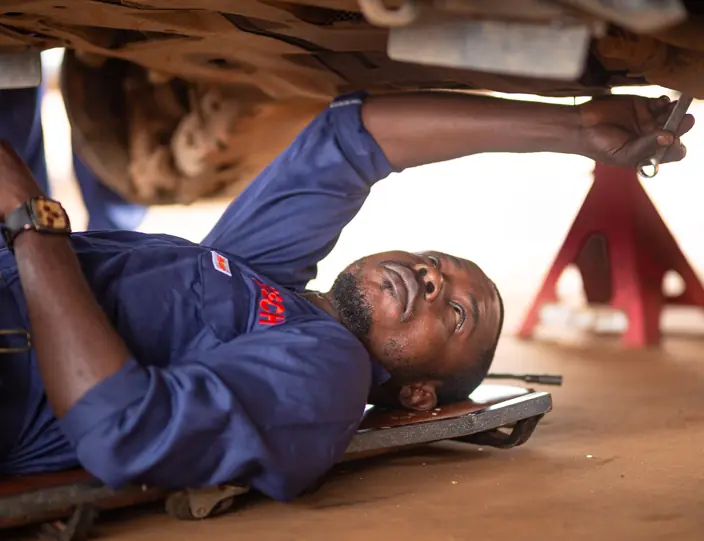 Technician on a creeper servicing a vehicle
